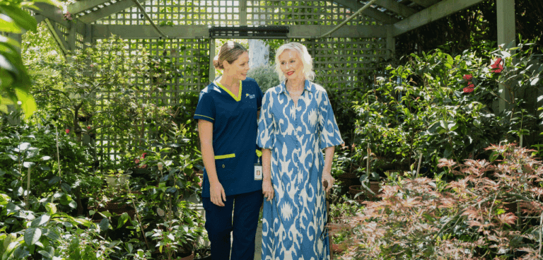 Prestige client walking through her garden with her carer