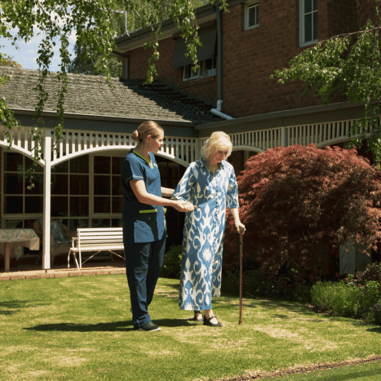 Prestige client walking through her garden with the help of her carer